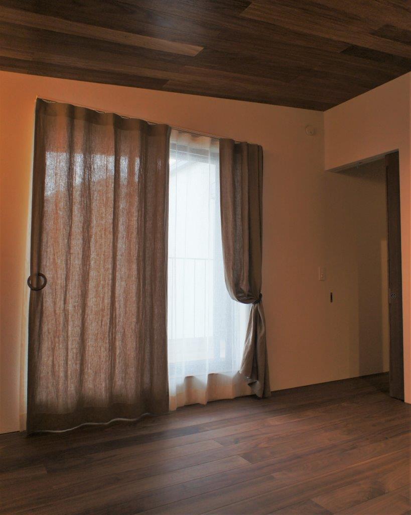 寝室に深みのあるサンドベージュ色のアースカラーリネンのドレープカーテン